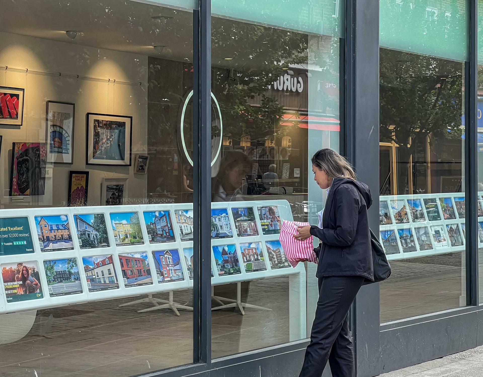 Woman looks at property displayed in an estate agent's window