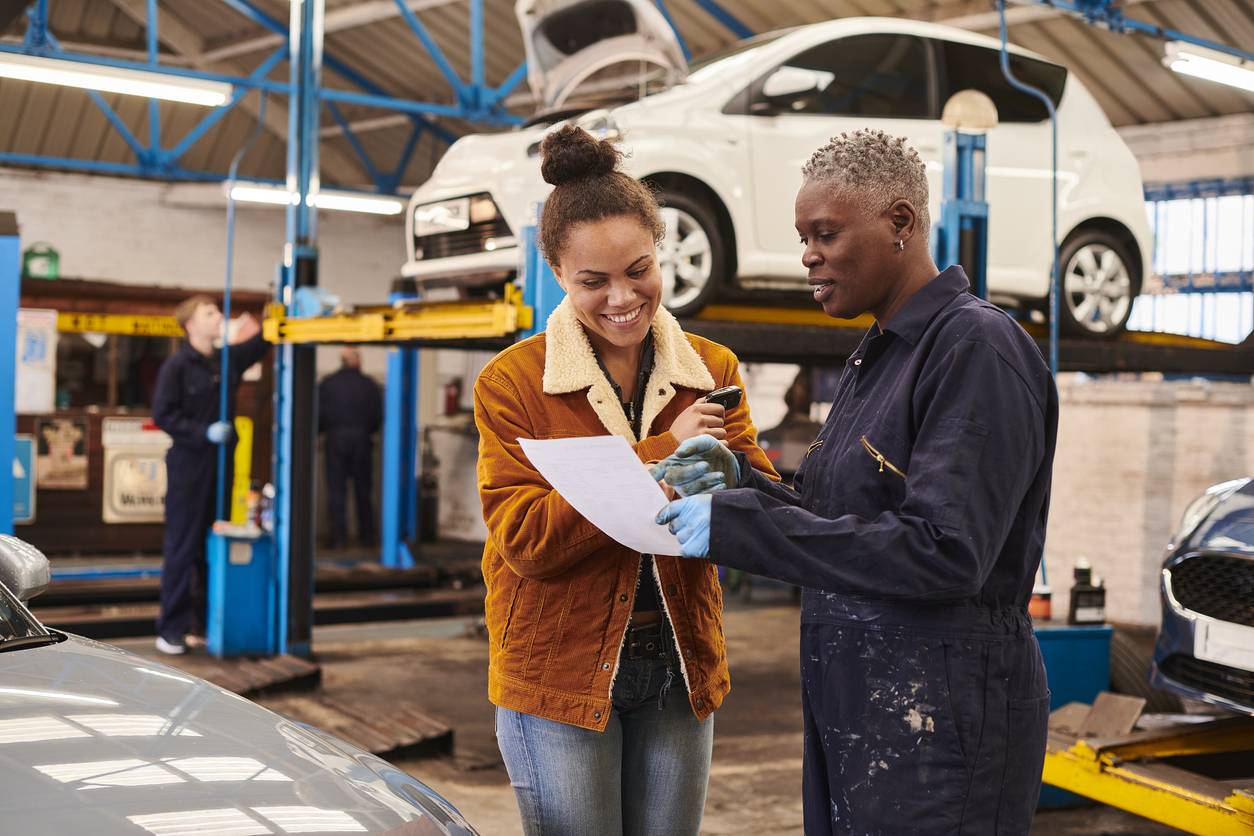 Mechanic discussing car service report with customer